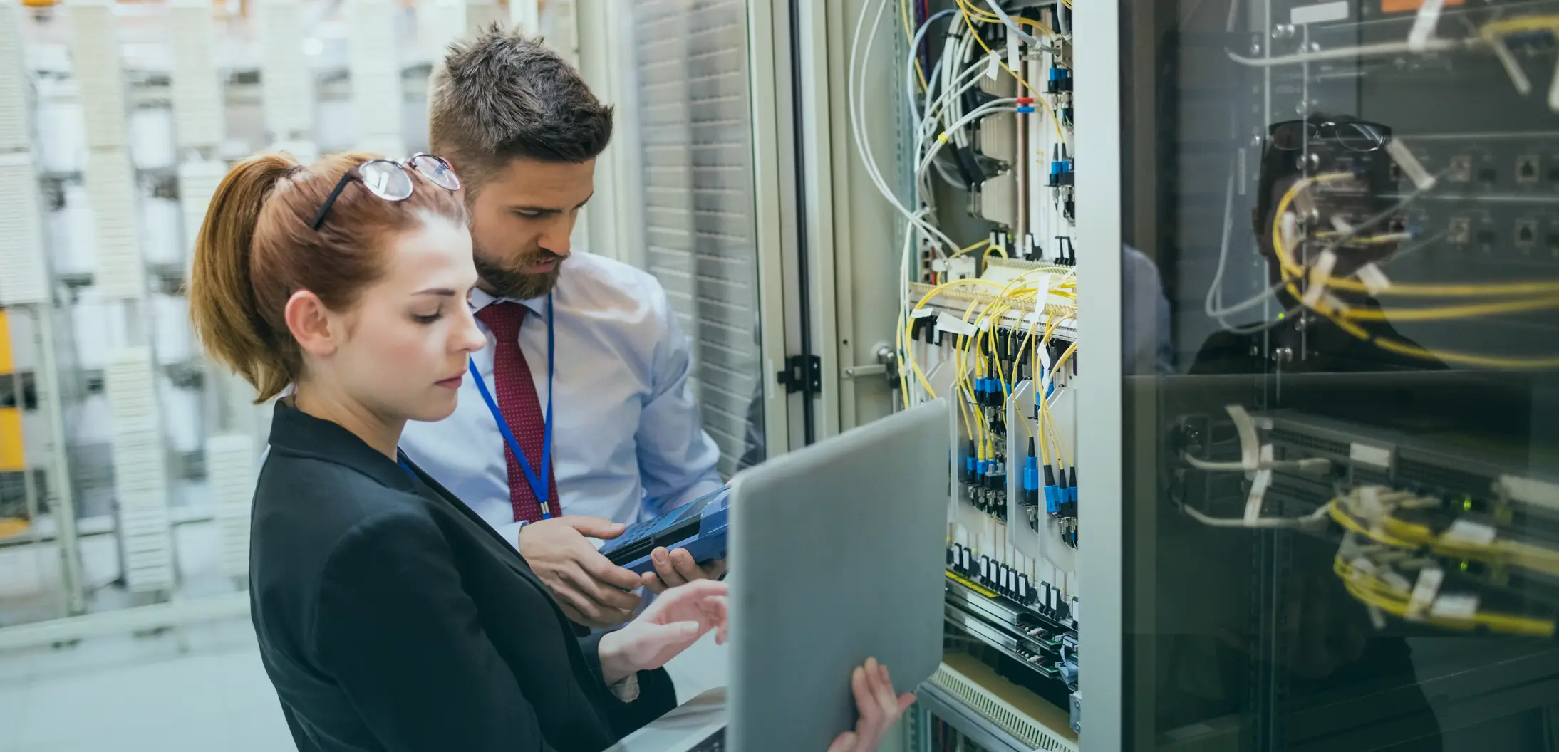 IT cost estimators collaborating in front of open server racks in a modern network data center during a preconstruction review.